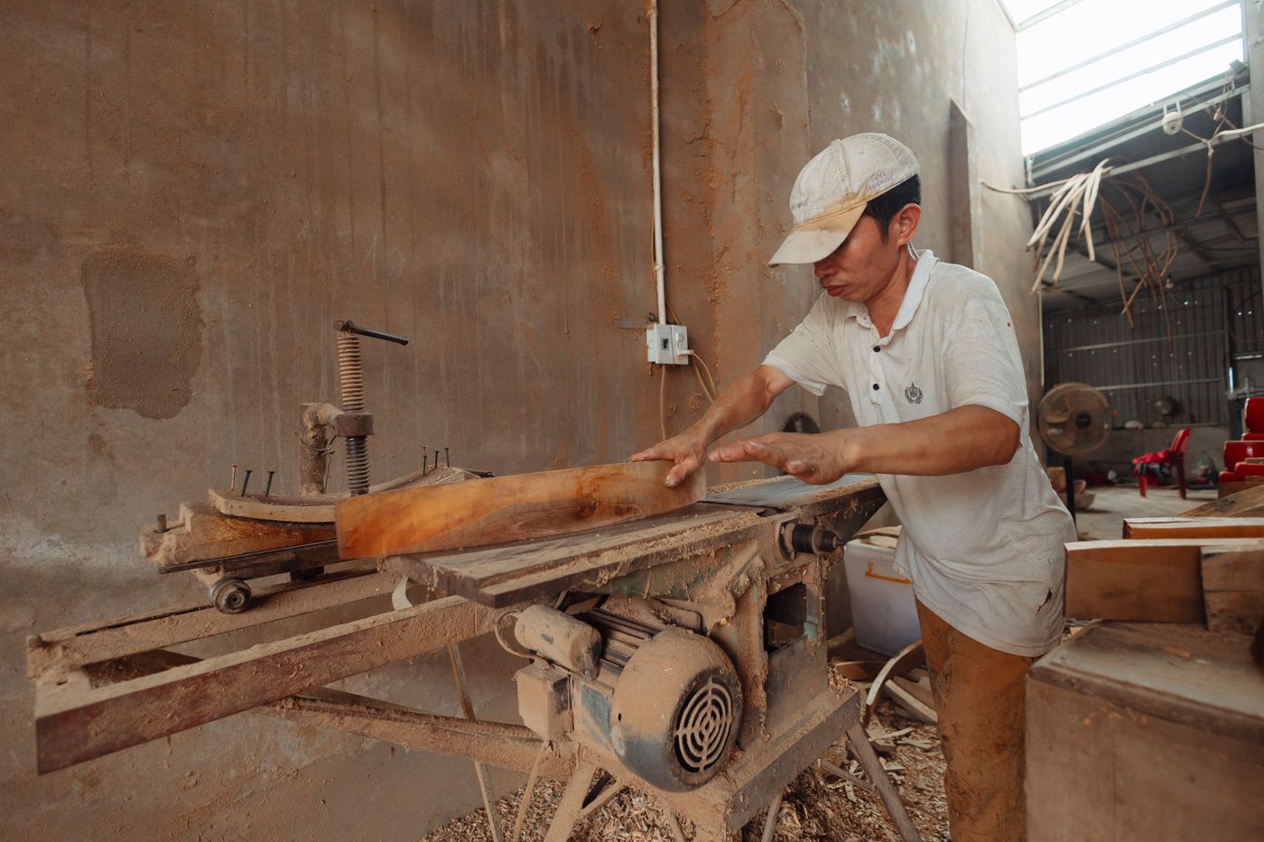 Man schaaft hout aan een machine in een werkplaats